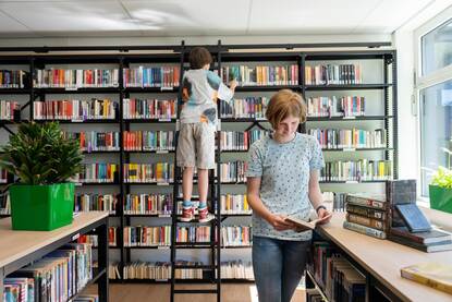 Twee leerlingen kiezen een boek in de schoolmediatheek