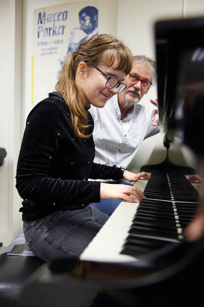 Leerling krijgt piano-instructie van leerkracht